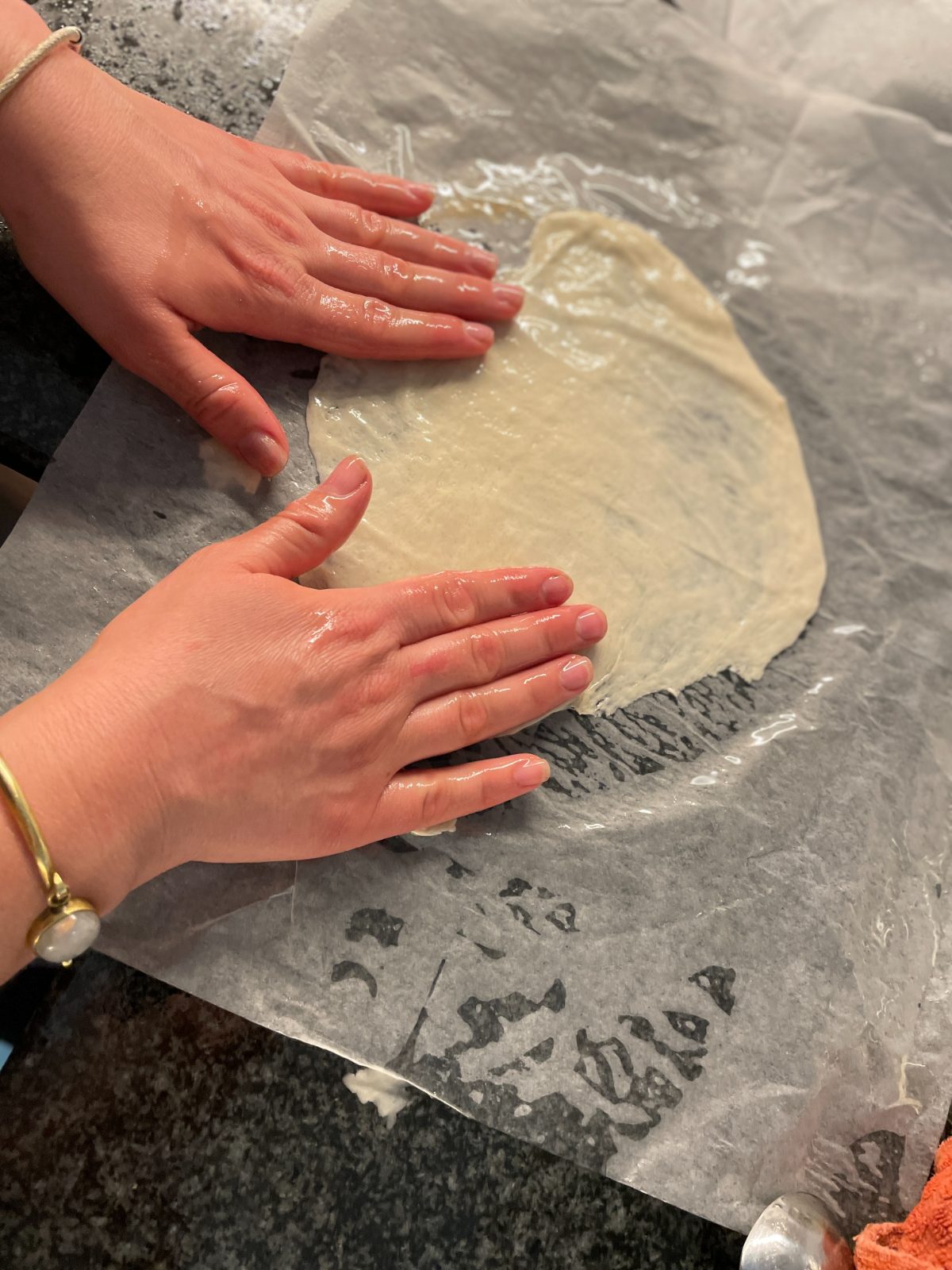 Hands pressing out dough on a floured counter